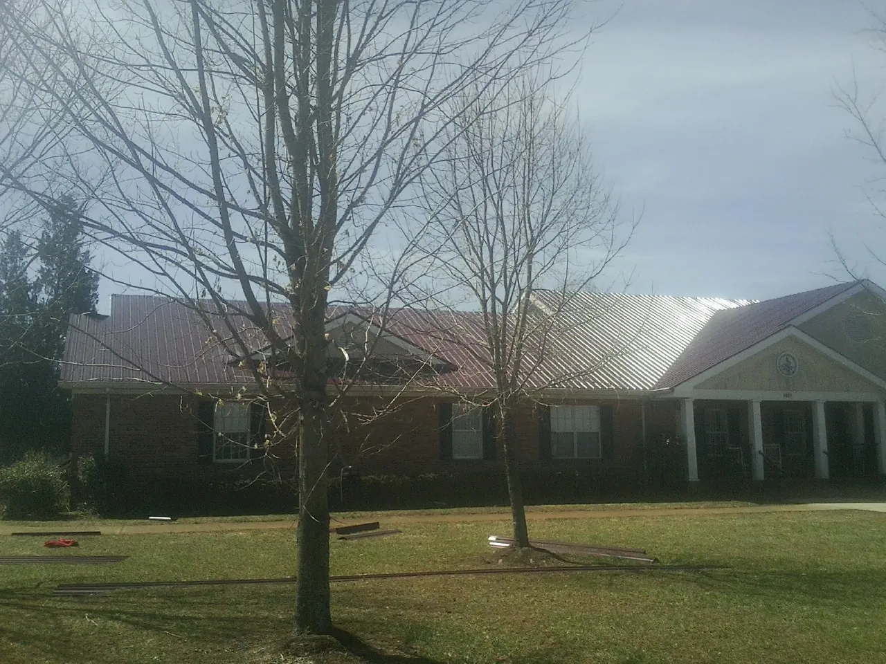 Red metal roof on a brick building seen from the front lawn in Coon Rapids