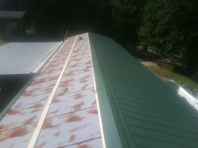 Old rusted panels beside newly installed green metal roofing — Wind Damage Roof Repair by Roofing Brothers in Coon Rapids