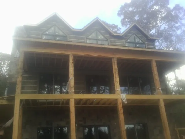 Dormers and porch framing on a large log home under construction — Roof Coating work by our crew in Coon Rapids