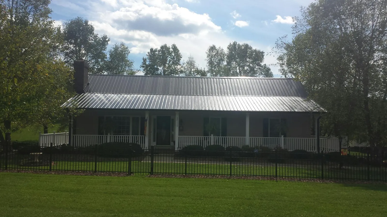 Gray metal roof on a brick ranch with a full width front porch — Gutter Guard Installation work by our crew in Coon Rapids