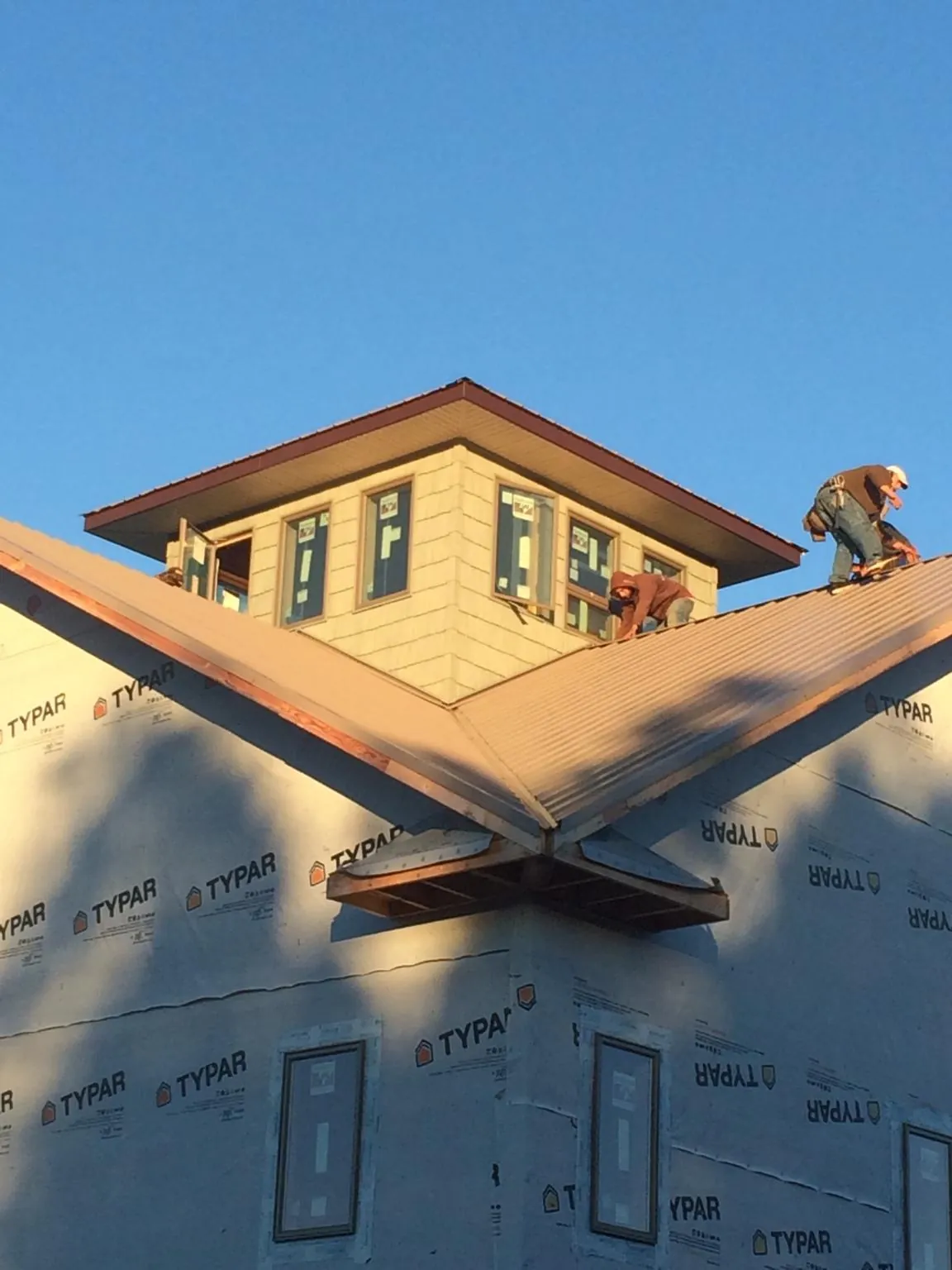 Roofers working around a rooftop cupola on a new metal roof at sunset — Roof Waterproofing in Coon Rapids by Roofing Brothers